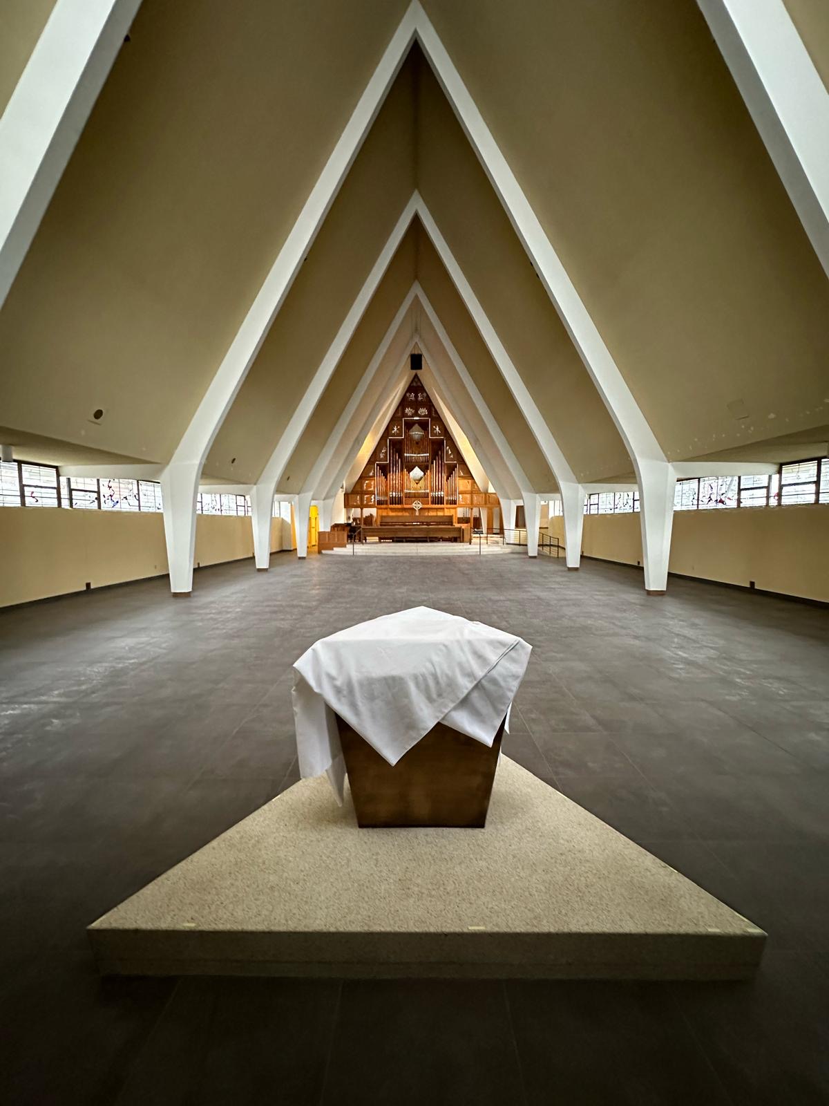 Renovated church sanctuary with soaring white A-frame arches, pipe organ, and stained-glass clerestory windows